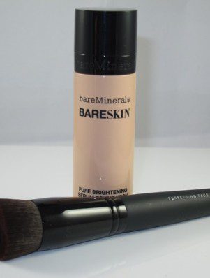 A bottle of foundation and a brush on top of the table.