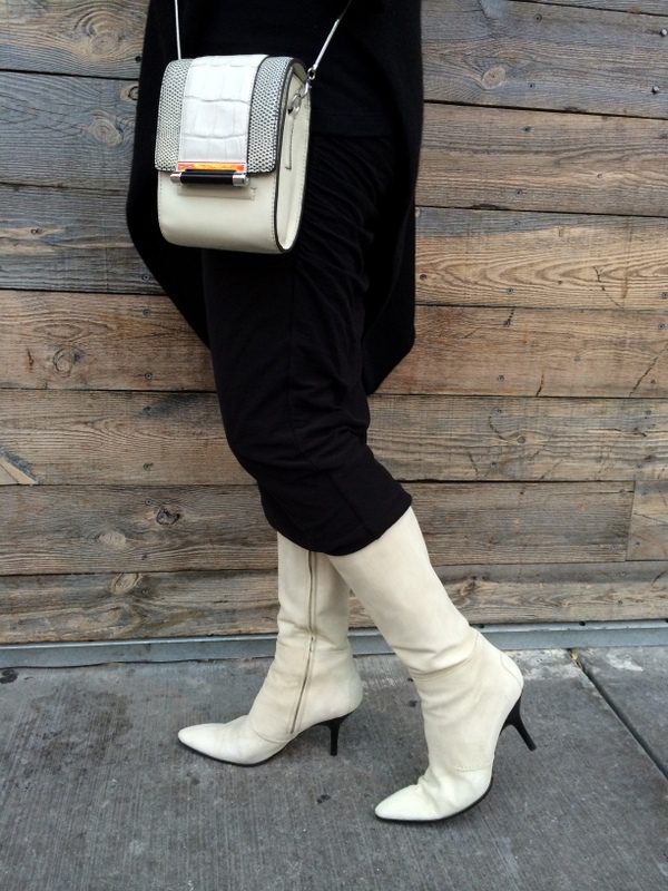 A woman wearing white boots and carrying a purse.
