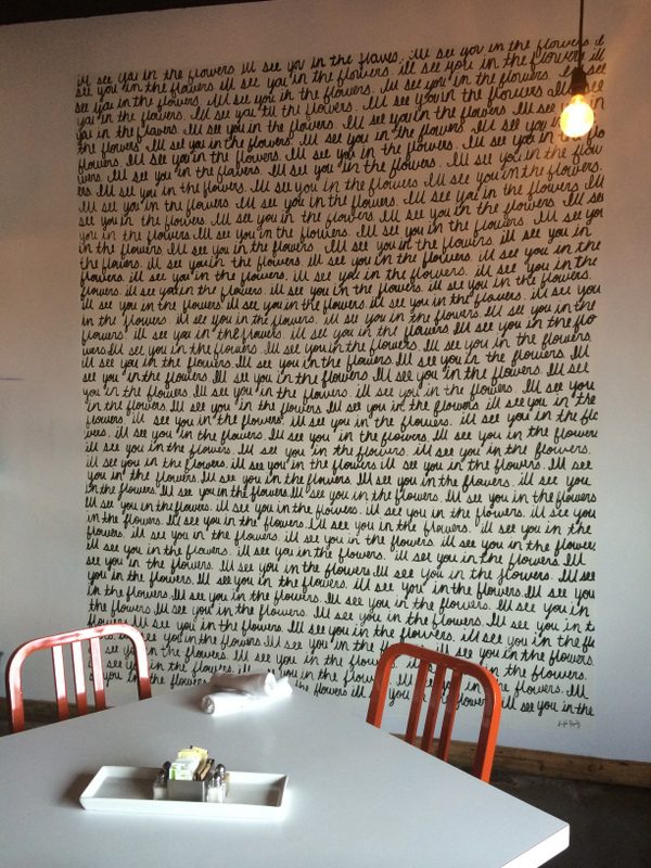 A wall with writing on it and two chairs in front of the walls.