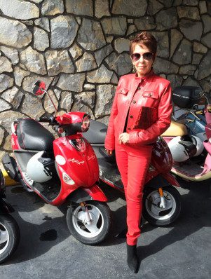 A woman in red standing next to parked motorcycles.