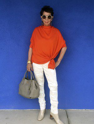 A woman in an orange top and white pants.