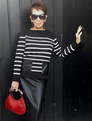 A woman in black and white striped shirt holding purse.