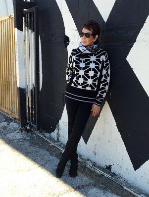 A woman standing in front of a wall with a black and white sweater.