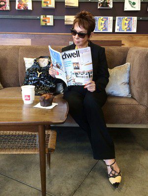 A woman sitting on the couch reading a magazine.