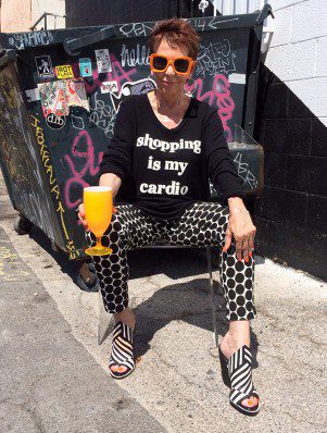 A woman sitting on the ground with a glass of orange juice.