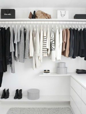 A white closet with clothes hanging on the rail.