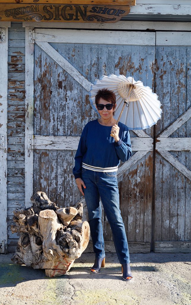 A woman holding an umbrella standing next to wood.