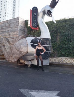 A woman in black lingerie standing next to an ostrich.
