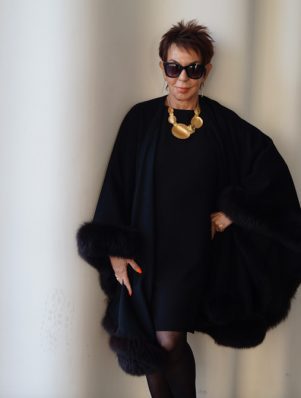 A woman in black dress and fur cape.