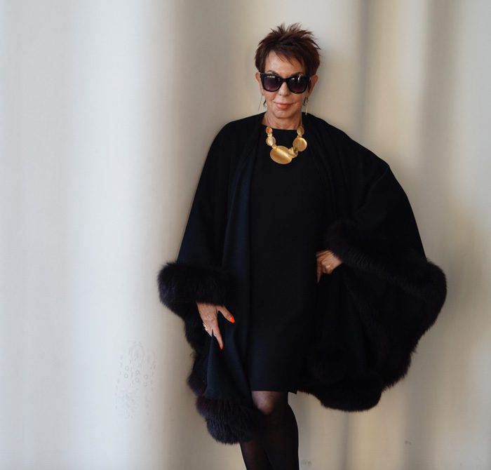 A woman in black dress and fur cape.