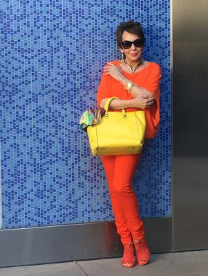 A woman in orange and yellow holding a bag.