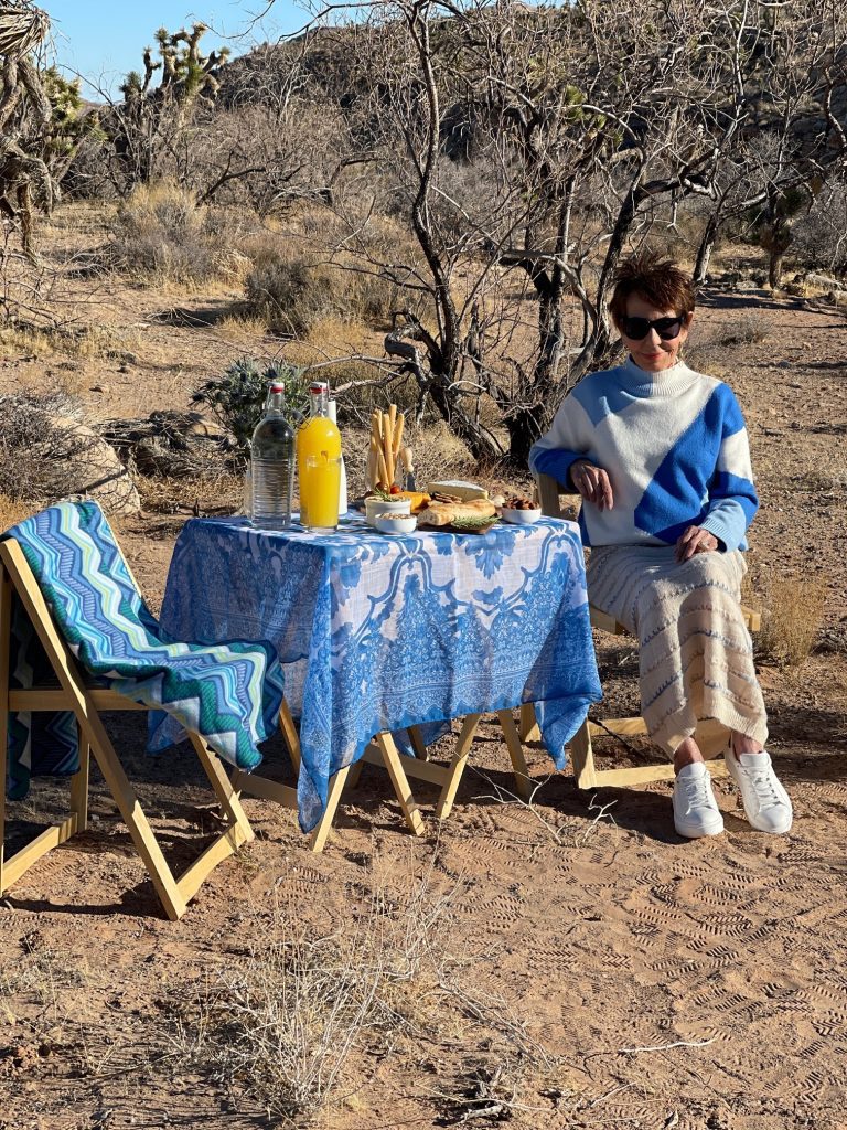 A man in blue shirt and hat standing next to table.