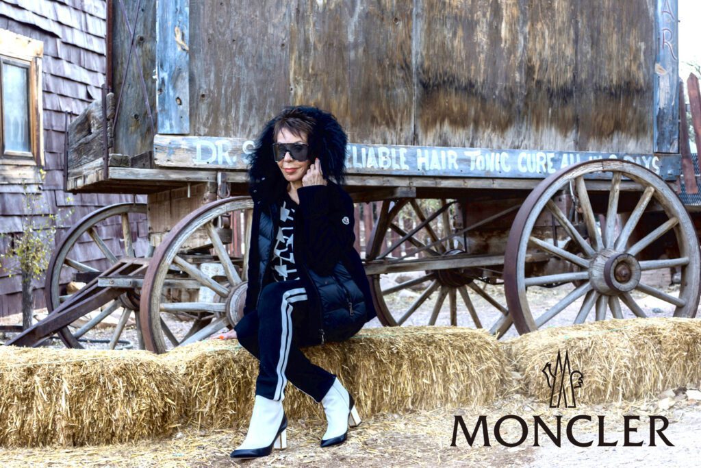A woman sitting on hay bales wearing white boots.